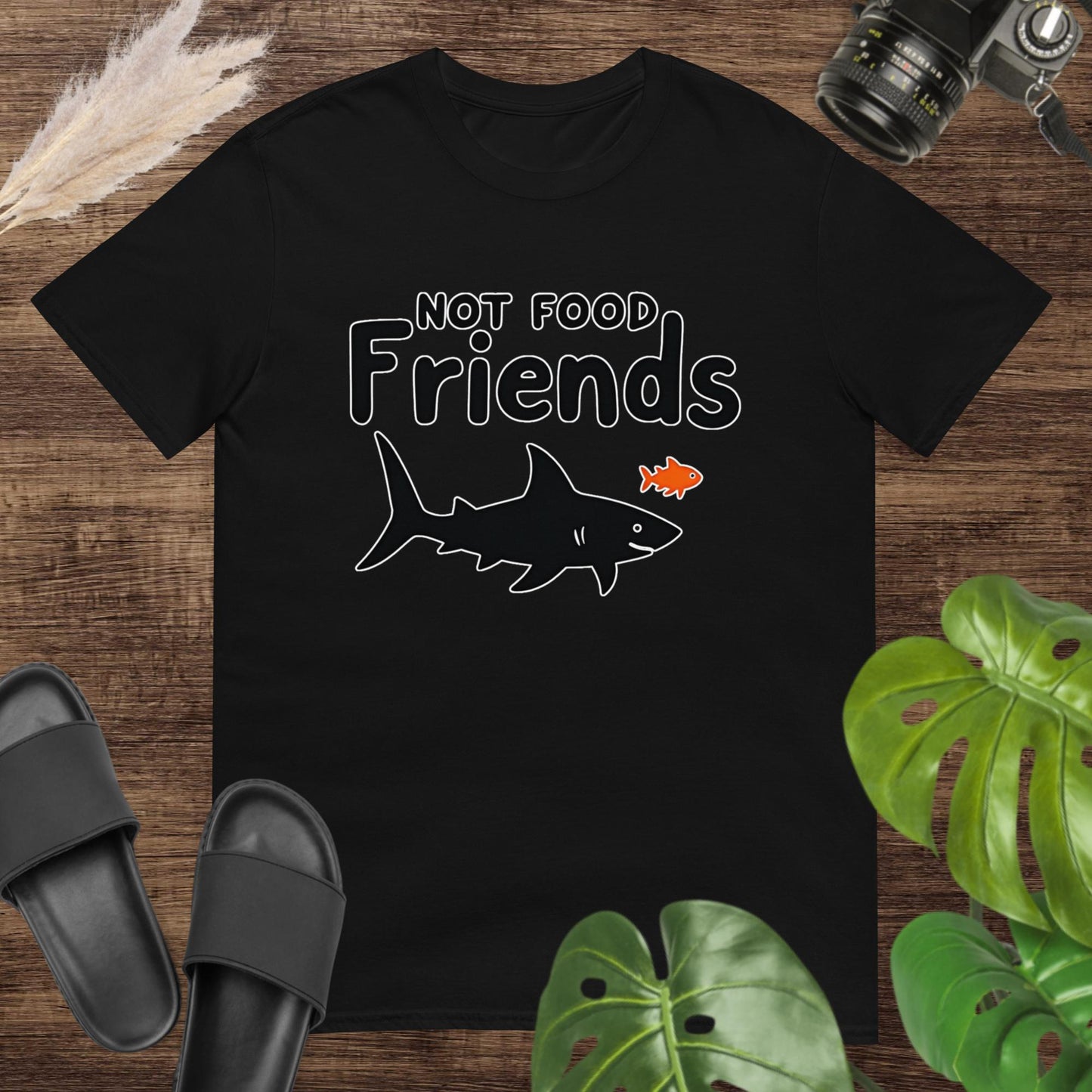 Black t-shirt featuring a shark and a small fish with the words “NOT FOOD Friends.”