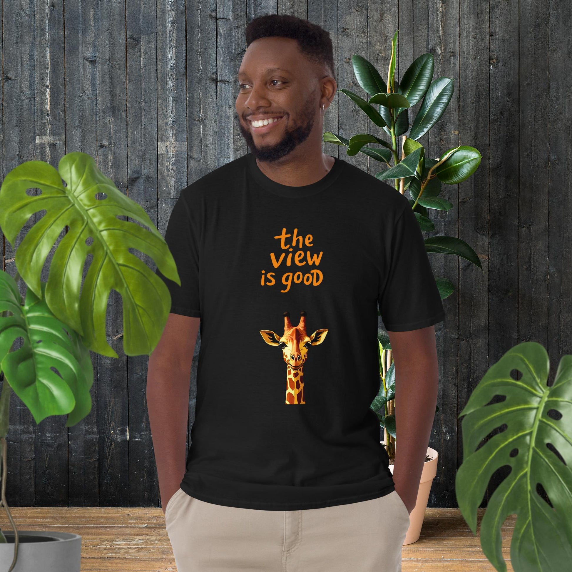Man wearing black unisex tee with giraffe graphic and 'the view is good' text, perfect for animal lovers