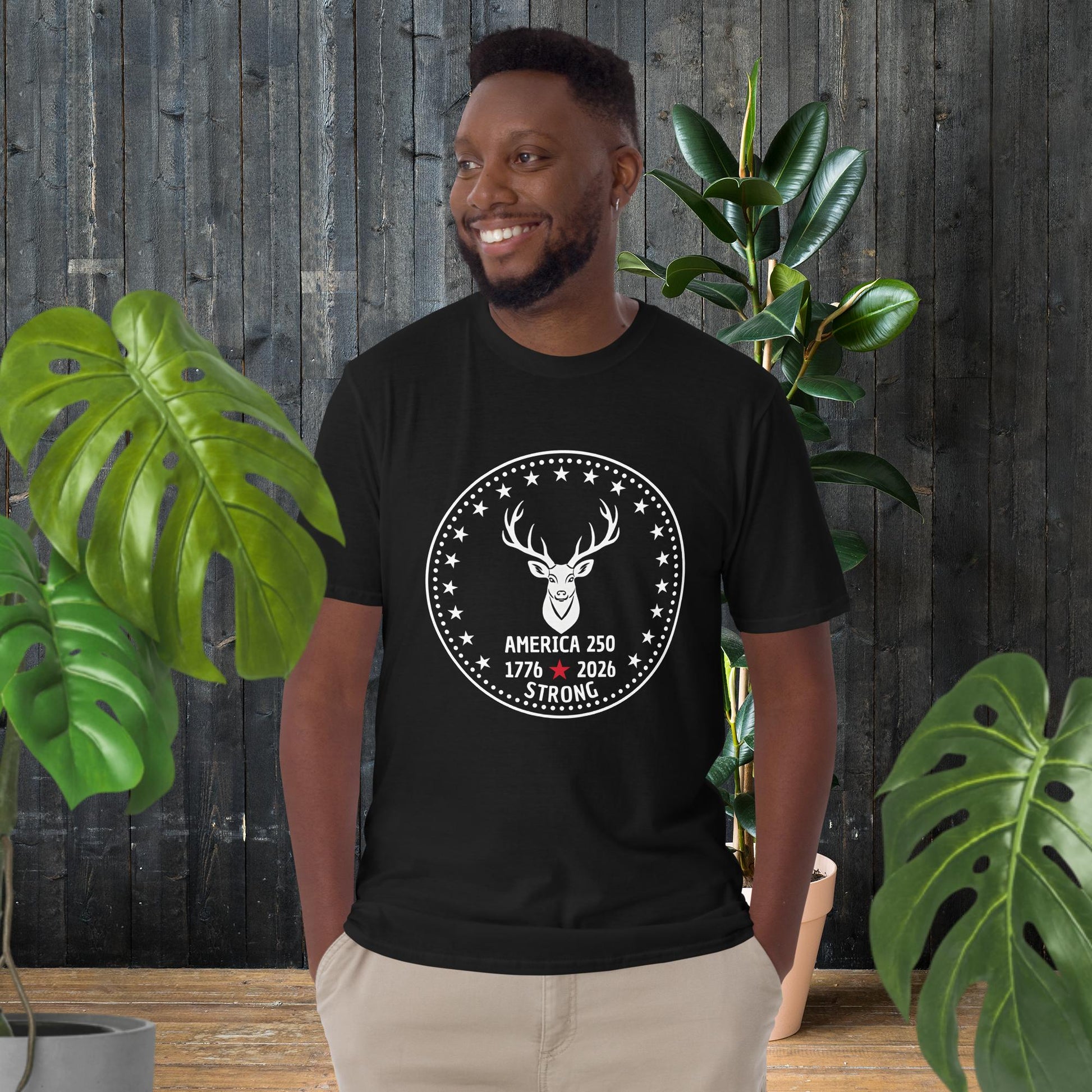 Man wearing black America 250 strong t-shirt with deer graphic, stars, and 1776-2026 text, unisex cotton tee