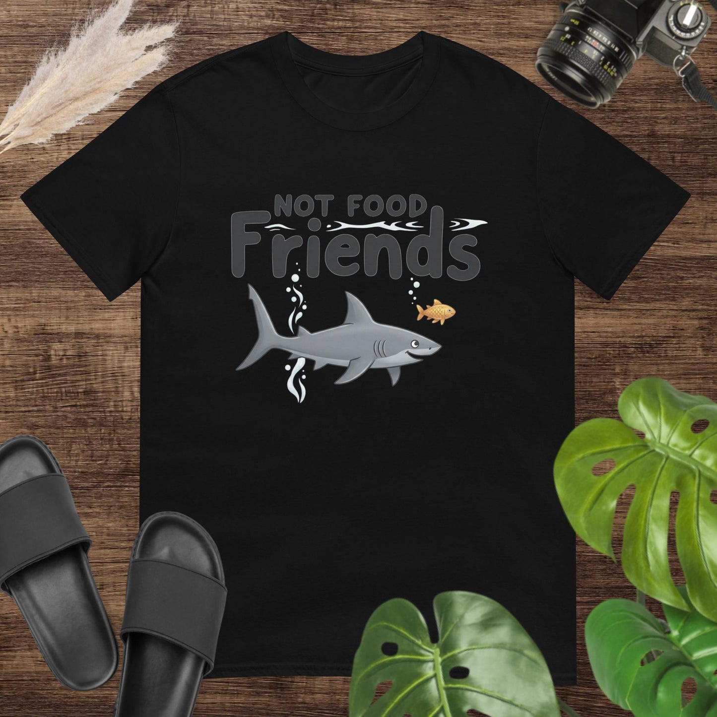 Black t-shirt featuring a shark and a small fish with the words “NOT FOOD Friends.”