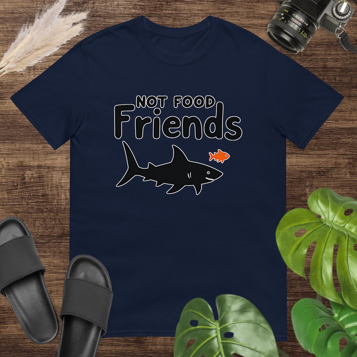 Navy t-shirt featuring a shark and a small fish with the words “NOT FOOD Friends.”