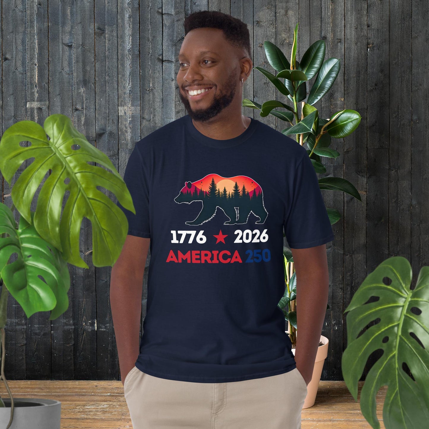 Man wearing navy t-shirt with bear silhouette, forest sunset, and '1776 2026 America 250' text