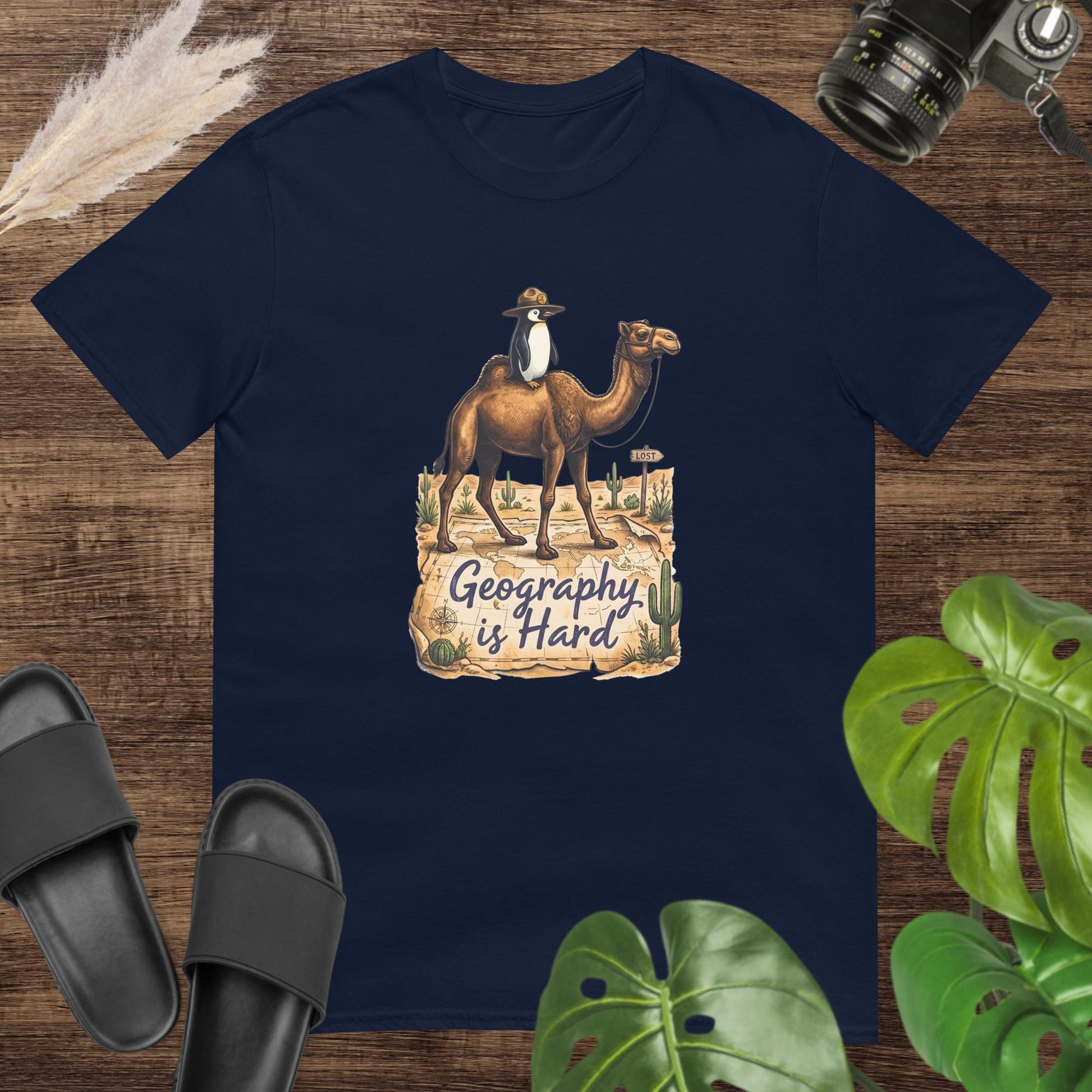Unisex navy t-shirt featuring a camel with a penguin on top and the text Geography is Hard.