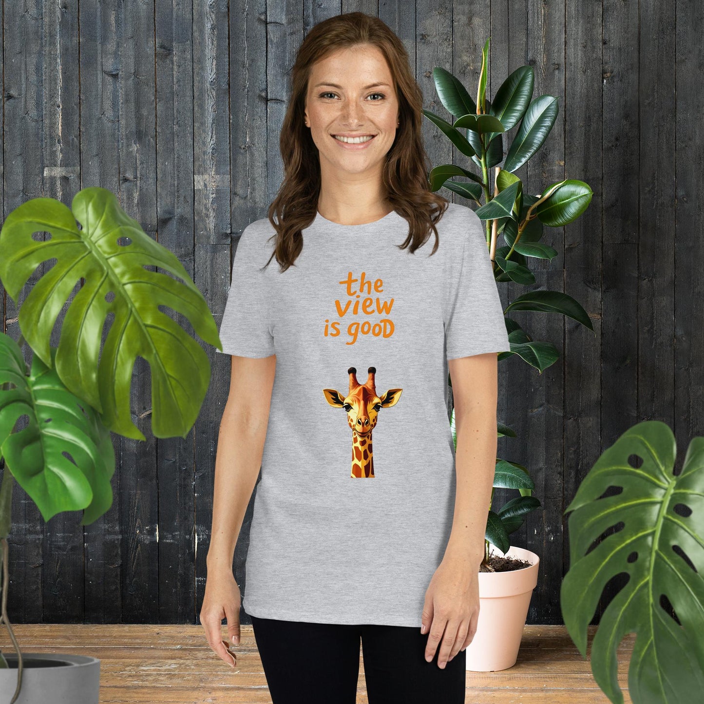 Woman wearing gray unisex tee with giraffe graphic and 'the view is good' text, perfect for animal lovers