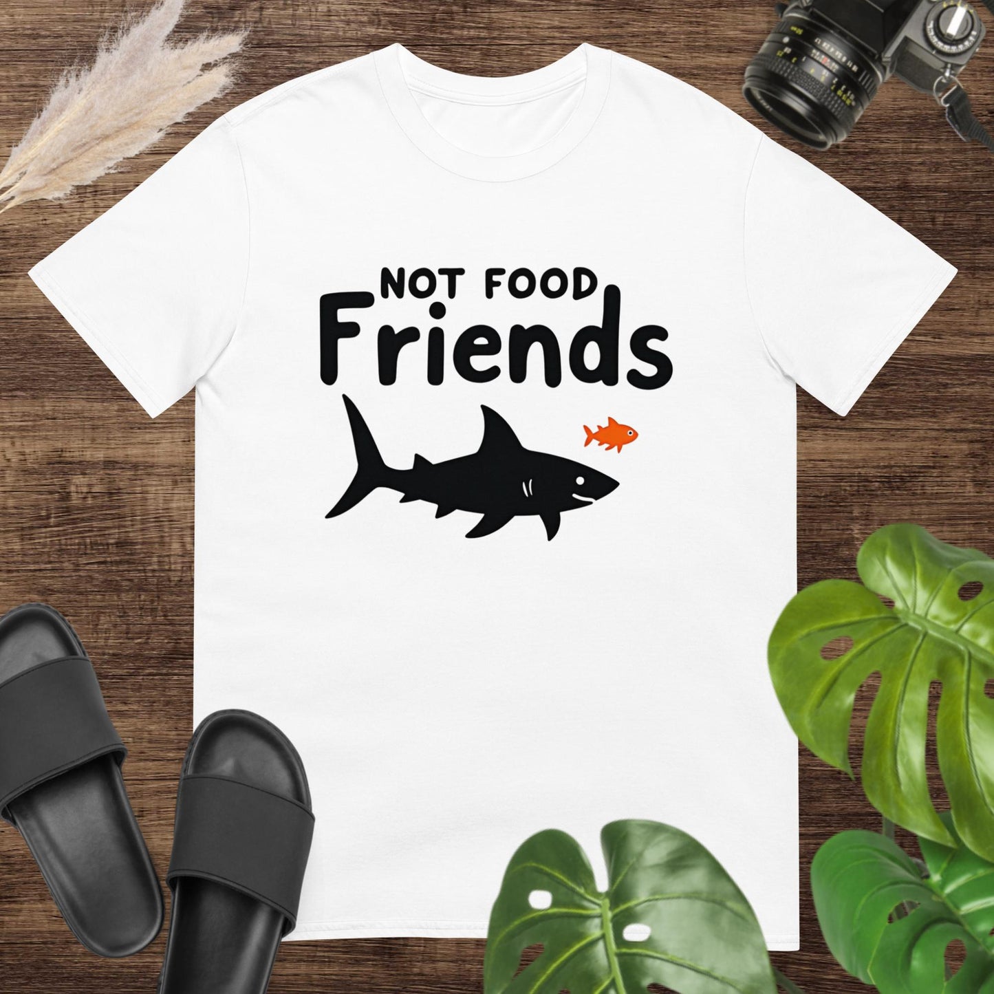 White t-shirt featuring a shark and a small fish with the words “NOT FOOD Friends.”